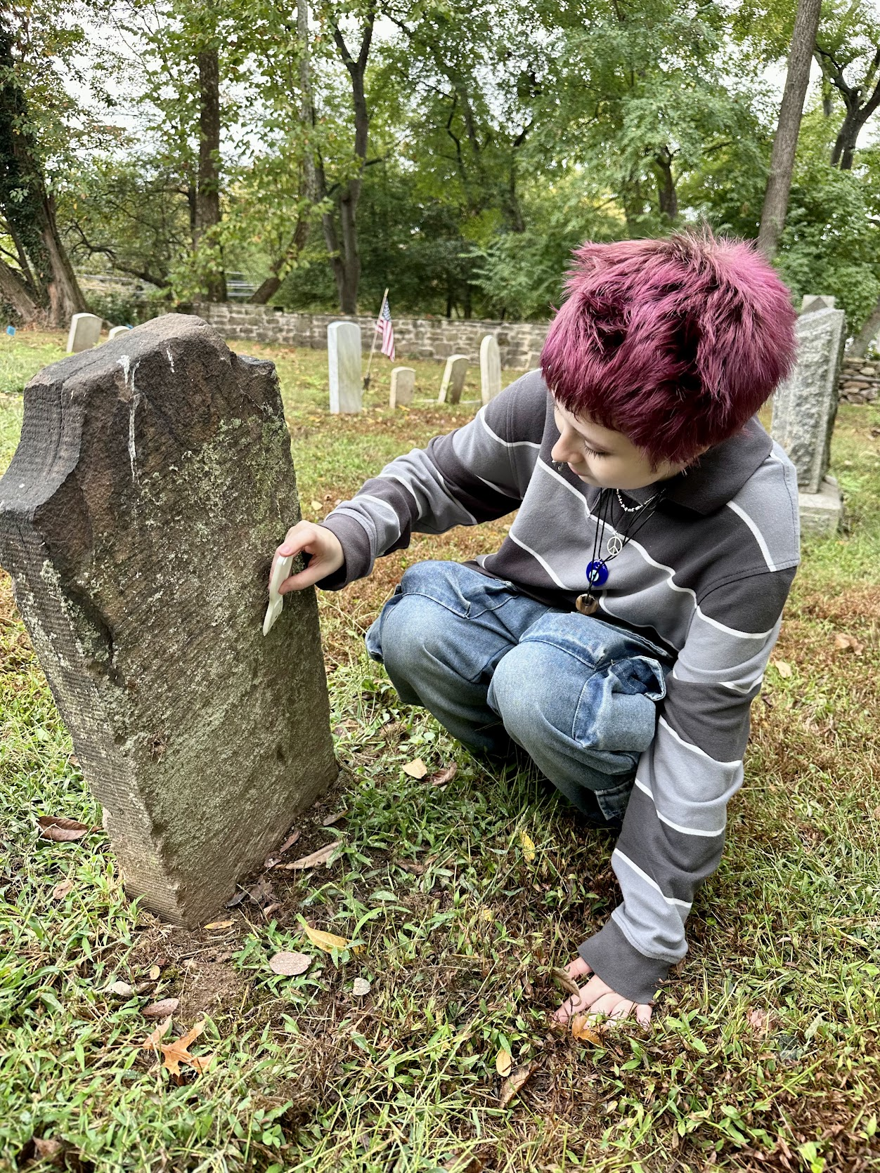 A teen examining a historic gravestone